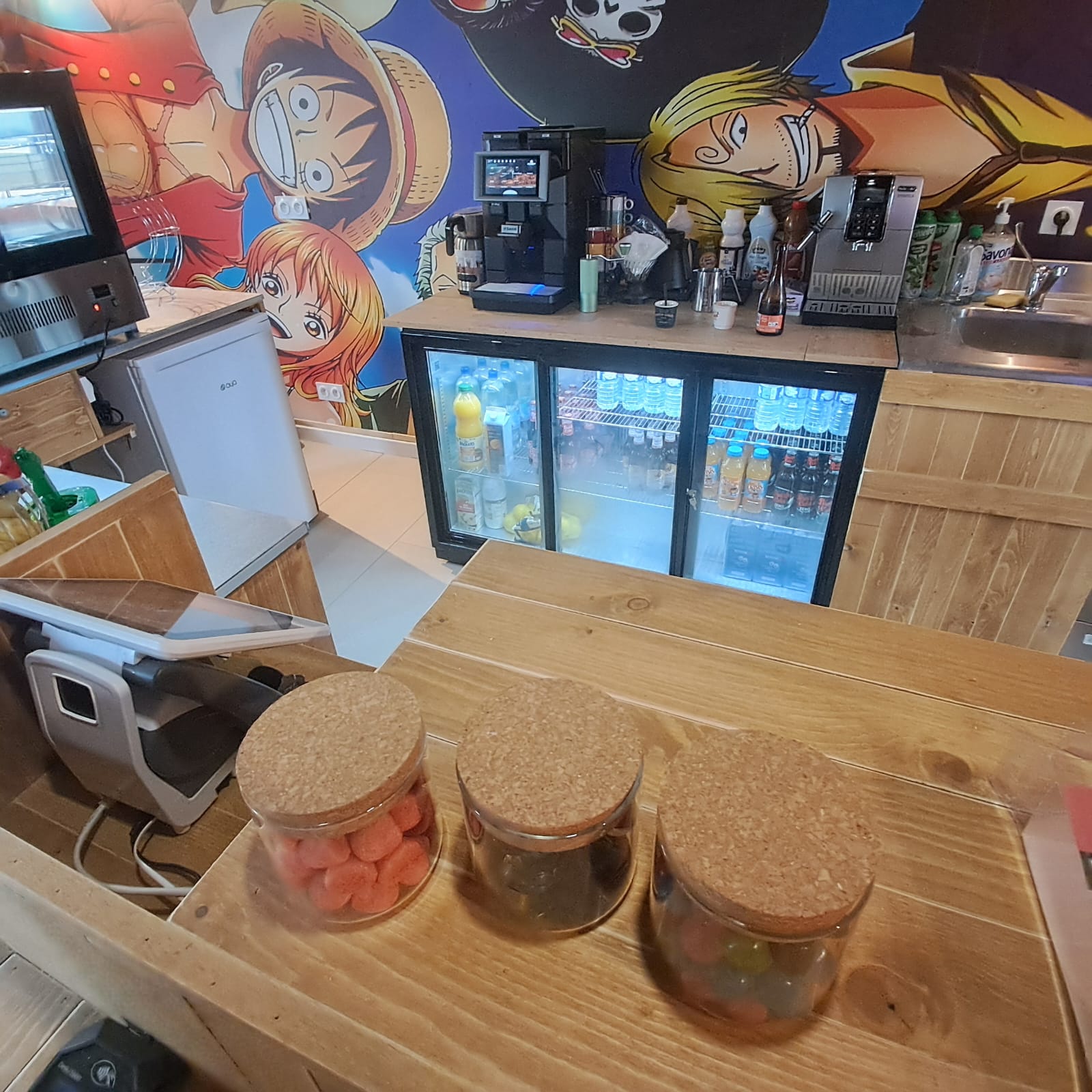 Photo du bar avec les machines à café et les frigo avec boissons